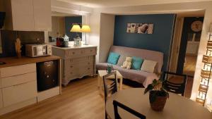 a kitchen and a living room with a couch and a table at Ma maison fleurie proche AEROPORT LYON ST EXUPERY, LDLC ARENA, Groupama Stadium,Eurexpo in Janneyrias