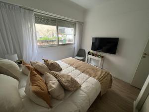1 dormitorio con 1 cama grande con almohadas y ventana en Apart Plaza Vicente Lopez en Buenos Aires