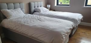 een slaapkamer met 2 bedden en witte dekbedden bij The Haggard Self Catering Accommodation in Castleblayney