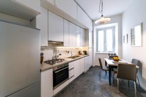 a kitchen with white cabinets and a table with chairs at Saint Peter House Station in Rome