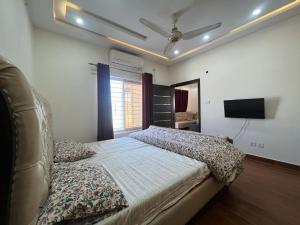 a bedroom with a bed and a ceiling fan at Haven Lodge, Family Suite with Lounge & Kitchen in Islamabad