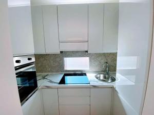 una cocina con armarios blancos y fregadero en Your Spacious & Lovely home -2 queen bed, 2 large single beds-, en Milán