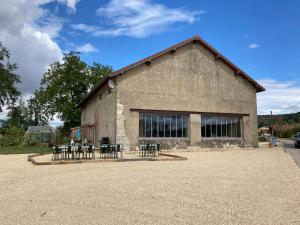 a building with tables and chairs in front of it at La Chambre du Tonneau in Montigny-sur-lʼAin