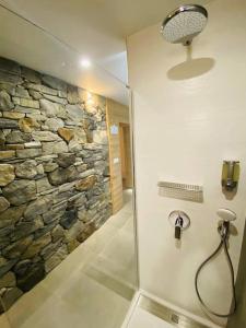 eine Dusche im Bad mit einer Steinmauer in der Unterkunft L‘atelier in Châtenois