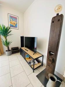 ein Wohnzimmer mit einem TV und einem Tisch in der Unterkunft L‘atelier in Châtenois