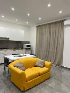 een woonkamer met een gele bank in een keuken bij Casa del Credente in Madonna dellʼArco
