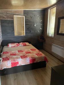 ein Schlafzimmer mit einem Bett mit einer Uhr an der Wand in der Unterkunft Къща за гости Голямо Дряново in Golyamo Dryanovo