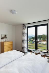 - une chambre avec un lit et une grande fenêtre dans l'établissement CHALET HOUBOVÝ VRCH, à Horní Planá