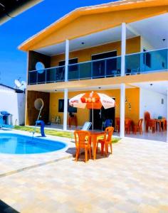 una casa con mesa, sillas y sombrilla en Aconchegante casa de praia em Paripueira/AL, en Paripueira