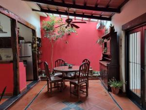 uma sala de jantar com uma parede vermelha e uma mesa e cadeiras em Hostal las Rosas em Salta