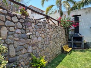 una pared de piedra con un banco y una lámpara en Hostal las Rosas en Salta