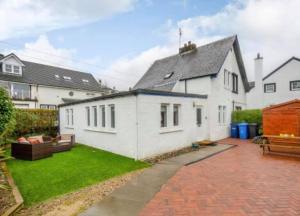 a white house with a patio and a yard at Cosy 3 bedroom home in centre of Brodick in Brodick