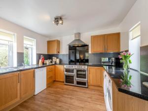 a kitchen with wooden cabinets and a stove top oven at Cosy 3 bedroom home in centre of Brodick in Brodick
