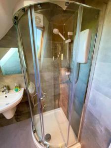 a shower with a glass door next to a sink at The Little Gable in Wavendon