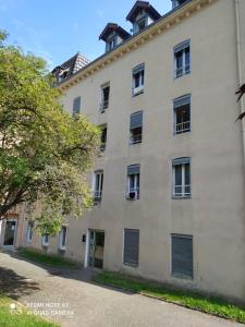 a large white building with windows and a tree at Joli studio au centre d'Uriage in Vaulnaveys-le-Haut