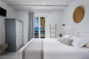 a white bedroom with a large bed and a window at Kalergis Studios in Naxos Chora