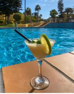 a drink in a martini glass next to a swimming pool at Corralejo Garden House in La Oliva