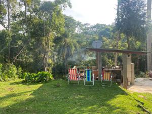 um grupo de cadeiras de jardim sentadas sob uma pérgola em Casa de campo com muito verde e paz/2 quartos/Wi-Fi/churrasqueira/ deck/ trilha/ minha cachoeira em Rio Acima