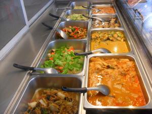 a row of trays filled with different types of food at Saengthong Resort Chiangmai in Chiang Mai