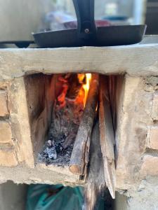 a fire in a brick oven with a pan on top at Casa de campo com muito verde e paz/2 quartos/Wi-Fi/churrasqueira/ deck/ trilha/ minha cachoeira in Rio Acima