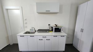 a white kitchen with a sink and a microwave at David Hameleh House in Netanya