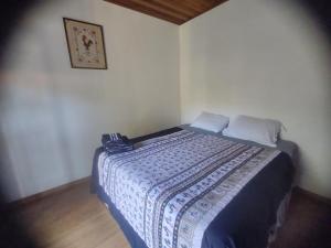1 dormitorio con 1 cama con manta azul y blanca en Casa de campo com muito verde e paz/2 quartos/Wi-Fi/churrasqueira/ deck/ trilha/ minha cachoeira en Rio Acima