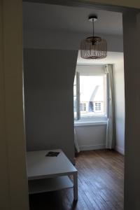 Cette chambre comprend une table, une fenêtre et un lustre. dans l'établissement Intra-Muros - T2 La Grande Hermine, à Saint-Malo