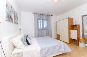 - une chambre blanche avec un lit et une armoire dans l'établissement Apartments Derado, à Supetar