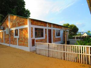 uma casa com uma cerca branca em frente em Moz T's Lodge em Inhambane