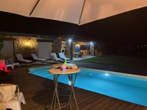 a patio with a table next to a swimming pool at night at VILLA SANTONI in Porticcio