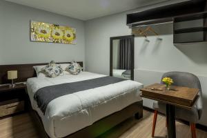 1 dormitorio con cama, mesa y espejo en Tikala Cusco Boutique Hotel, en Cusco