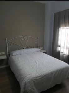 ein Schlafzimmer mit einem Bett mit einer weißen Bettdecke und einem Fenster in der Unterkunft Apart. con piscina a 5 min de la playa (el Ancla, Puerto de St. María) in El Puerto de Santa María