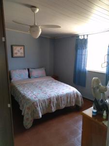 1 dormitorio con 1 cama y ventilador de techo en Casa dos passarinhos, en Arraial do Cabo