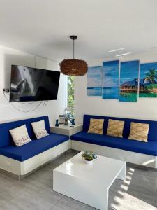 een woonkamer met een blauwe bank en een tv bij Deplaya Zorritos-Tumbes in Bocapán