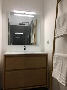 ein Badezimmer mit einem Waschbecken, einem Spiegel und Handtüchern in der Unterkunft L'arbousier in Cassis