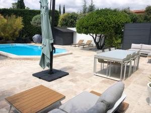 een patio met een tafel, een parasol en een zwembad bij L'arbousier in Cassis