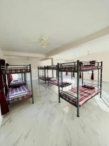 three bunk beds in a room with marble floors at Darshan Arrive & Revive Homestay. in Kushālnagar