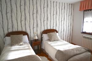 1 dormitorio con 2 camas y papel pintado con árboles en Casa La Quintana en Oceño