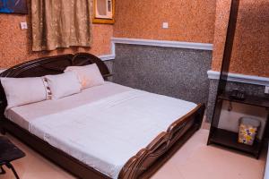 Schlafzimmer mit einem Bett mit einem Kopfteil aus Holz in der Unterkunft Double One Suites & Lodge in Ikeja