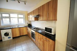 a kitchen with wooden cabinets and a microwave at Flexistay Tooting Studios in London