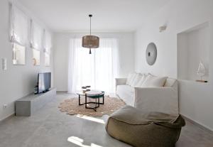 a white living room with a couch and a tv at Elements Villas in Lardos