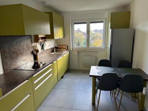 eine Küche mit gelben Schränken und einem Tisch mit Stühlen in der Unterkunft Vaste appartement cosy avec parking gratuit et espace de travail in Illkirch-Graffenstaden