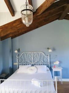 sypialnia z białym łóżkiem i niebieską ścianą w obiekcie La casa de verano Cudillero w mieście Cudillero