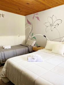 two beds in a room with a painting on the wall at MAKTUB HOSTERIA in El Bolsón