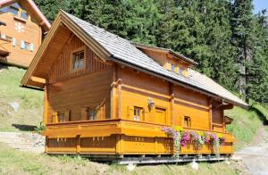 a large wooden house with flowers in front of it at Bioblockhaus Katschberg in Katschberghöhe