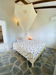 1 dormitorio con 1 cama blanca con sombrilla en Villa Kara, en Grand-Bourg