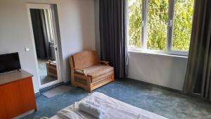 a bedroom with a chair and a tv and a window at Family Hotel Saga in Ravda