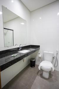 a bathroom with a toilet and a sink and a mirror at Euro Flat Hotel in Parnaíba