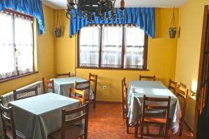 comedor con 2 mesas, sillas y ventanas en Casa La Quintana, en Oceño