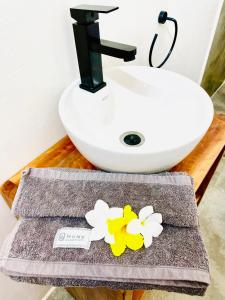 a bathroom with a sink and a towel with flowers at Butterfly Apartment Zanzibar in Bwejuu